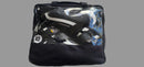 A black zippered shoe bag with a clear front window, containing several black and white sneakers, laid flat on a gray textured fabric surface.